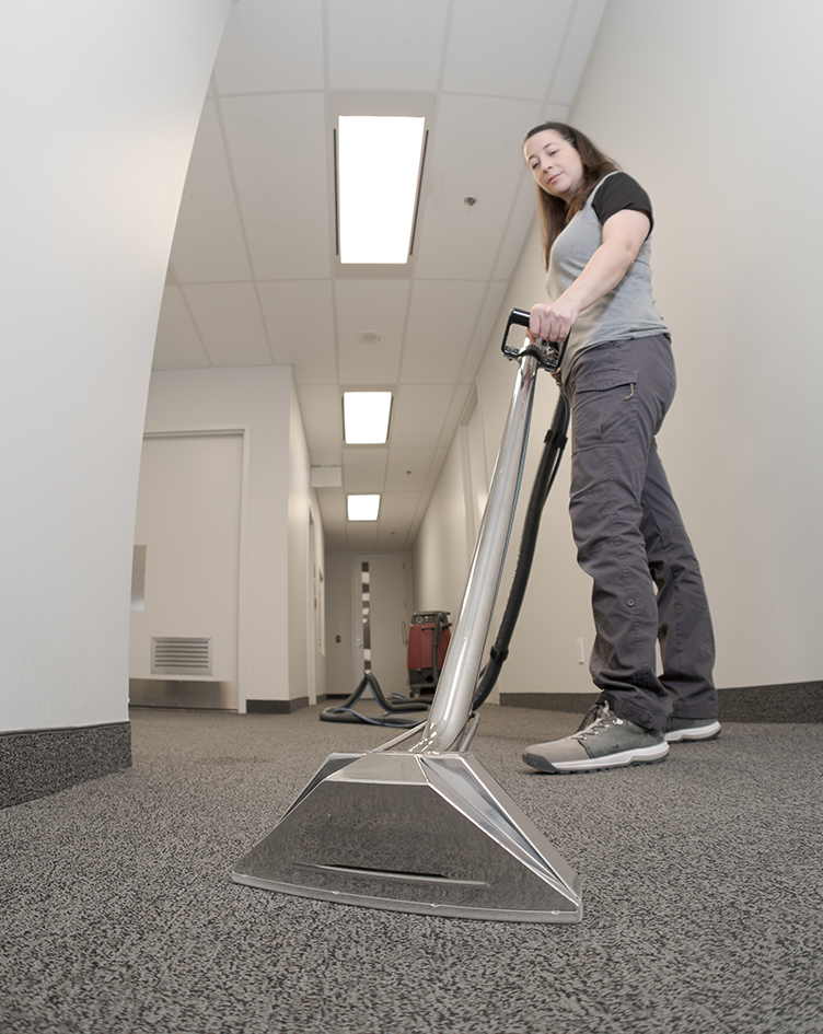 female cleaner employee removing dirt from carpet